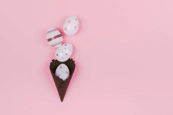 Easter eggs in black ice-cream horn on pastel pink background. Flat lay, Easter concept. — Zdjęcie stockowe