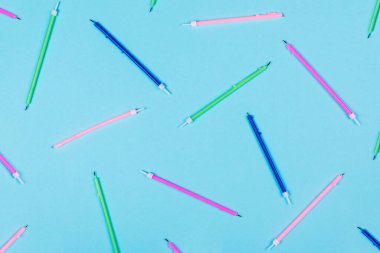 Pastel mavisi arka planda renkli doğum günü mumları ve fotokopi alanı olan desen. Yaratıcı ve karamsar bir tablo. Üst görünüm.