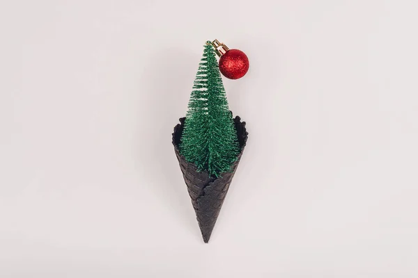 Miniatur Weihnachtsbaum Mit Roter Kugel Aus Schwarzem Eishorn Auf Pastellfarbenem lizenzfreie Stockbilder