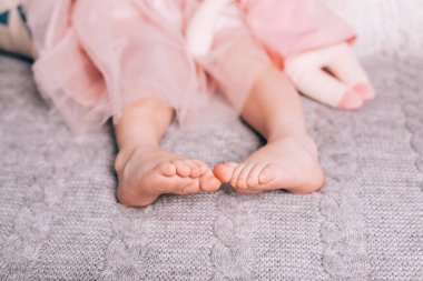 Yumuşak oyuncakla sıcak örülmüş battaniyeye uzanmış şirin, çıplak ayaklar. Evdeki rahat zaman, yaşam tarzı..