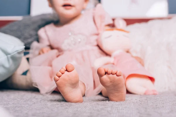 Söta små barn bara fötter liggande på varm stickad filt med mjuk leksak. Mysig tid hemma, livsstil. — Stockfoto