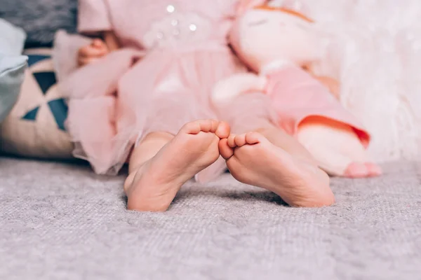 Söta små barn bara fötter liggande på varm stickad filt med mjuk leksak. Mysig tid hemma, livsstil. — Stockfoto