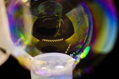 Soyutlama. Siyah arka planda suyun üzerinde sabun köpükleri. Renk oyunu. Bulanık renkli baloncuklar. Yakın plan..