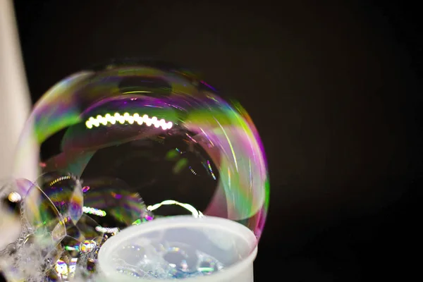 Абстракция. Мыльные пузыри на воде на черном фоне. Цветовая игра. Размытые разноцветные пузыри. Крупный план . — стоковое фото