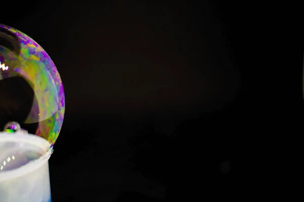 Abstracción. Burbujas de jabón en el agua sobre un fondo negro. El juego de colores. Burbujas borrosas multicolores. Primer plano . — Foto de Stock