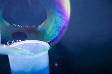 Soyutlama. Siyah arka planda suyun üzerinde sabun köpükleri. Renk oyunu. Bulanık renkli baloncuklar. Yakın plan..