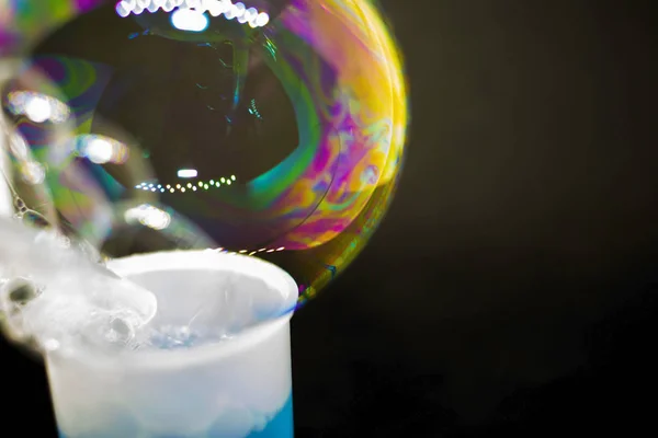 Abstracción. Burbujas de jabón en el agua sobre un fondo negro. El juego de colores. Burbujas borrosas multicolores. Primer plano . — Foto de Stock