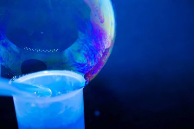 Soyutlama. Siyah arka planda suyun üzerinde sabun köpükleri. Renk oyunu. Bulanık renkli baloncuklar. Yakın plan..