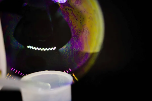 Abstractie. Zeepbellen op het water op een zwarte achtergrond. Het spel van kleuren. Wazige veelkleurige bellen. Close-up. — Stockfoto