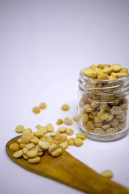 Dry peas are scattered from a jar on a wooden spoon on a white background. Close-up. Bio healthy and diet food. Selective focus.