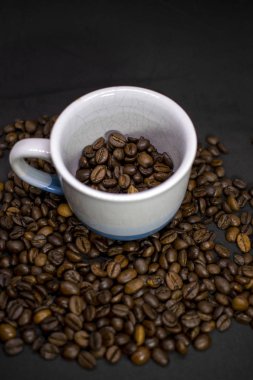 Coffee cup with grains against dark background. Close-up with copy space for your text.