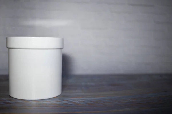 Pot en plastique blanc sur une table en bois sur un fond de mur de briques blanches. Espace de copie. place pour le texte — Photo