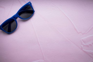 Blue darkened, sunglasses on a pink background. ultra minimal. flat lay fashion summer.