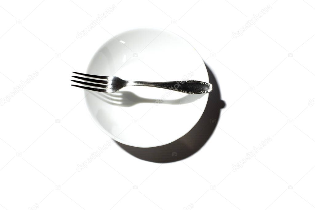White round plate with a metal fork on a white background