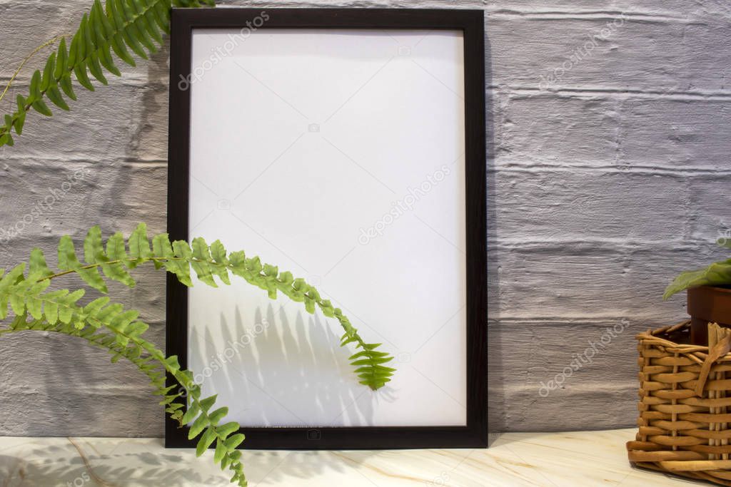 Front view of a blank mockup of black photo frame on brick wall background. A cup of coffee, flowers.
