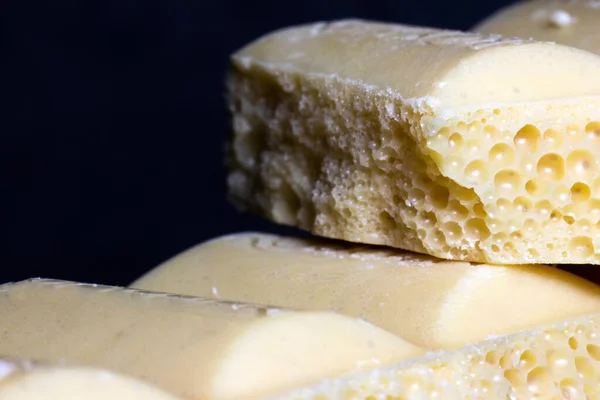 Broken bar of white chocolate on a black background. A delicious bar of milk chocolate. Selective focus