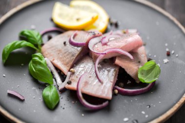 Kırmızı soğan, limon ve fesleğen ile marine edilmiş ringa balığı.