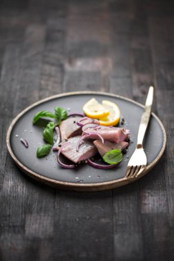 Kırmızı soğan, limon ve fesleğen ile marine edilmiş ringa balığı.