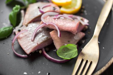Kırmızı soğan, limon ve fesleğen ile marine edilmiş ringa balığı.