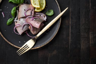 Kırmızı soğan, limon ve fesleğen ile marine edilmiş ringa balığı.