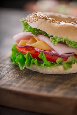 Bagel sandwich with salad, tomato, yellow cheese and ham clipart