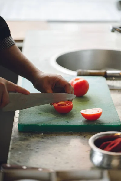 chef cuts tomatoes on the kitchen board