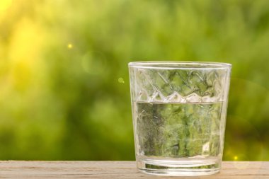 Yeşil Bokeh 'in ahşap arka planında bir bardak su
