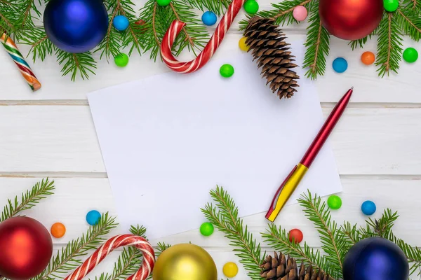 Christmas back,ground, green fir branches, red and blue, yellow, ball, candies, cone, white sheet and a pen, white boards, frame pattern