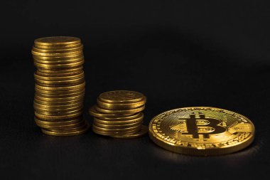 Üç yığınları sikke sipariş ve bir altın sikke bitcoin siyah deri üzerinde artan