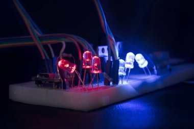 breadboard arduino nano prototyping board transistors resistors LEDs red and blue in glow in the dark on black skin clipart