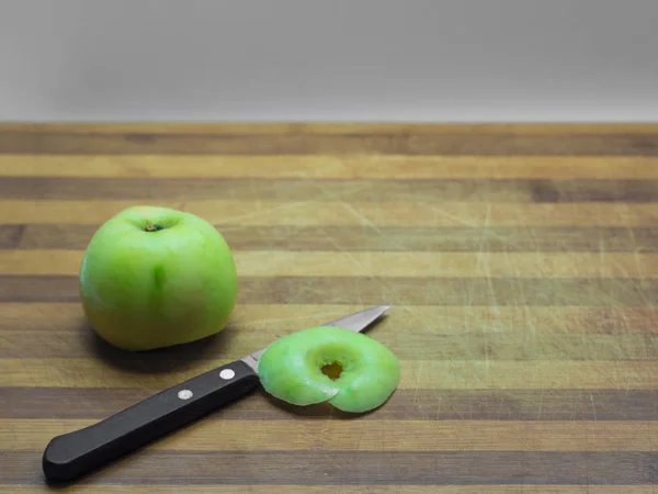 Grüner Apfel ganz und Scheiben auf einem Holzbrett, ein Messer mit einem — Stockfoto