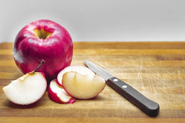 Roter Apfel ganz und Scheiben auf einem Holzbrett, ein Messer mit einem — Stockfoto