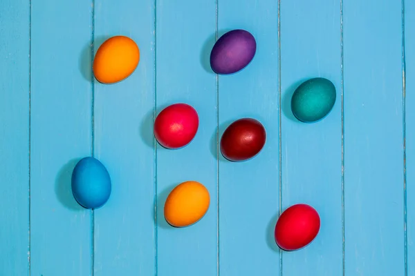 Colored Easter eggs on light blue wooden boards top view. red, b — Stock Photo, Image