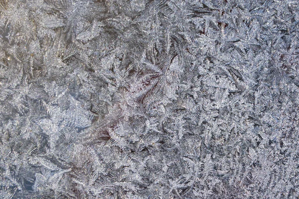 Padrão de gelo flocos de neve com luz solar no vidro da janela de inverno — Fotografia de Stock