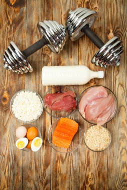 Protein, balık, peynir, yumurta, et, tavuk ve ahşap arka plan üzerinde halter