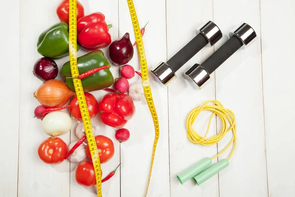 Sport e dieta. Uno stile di vita sano. Verdure, manubri. Peperoni, pomodori, aglio, ravanelli di cipolle su fondo bianco — Foto Stock