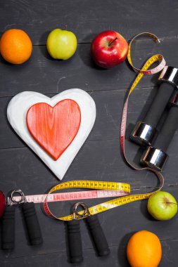 Kalp, meyve ve halter. Fitness, sağlıklı bir yaşam tarzı siyah ahşap zemin