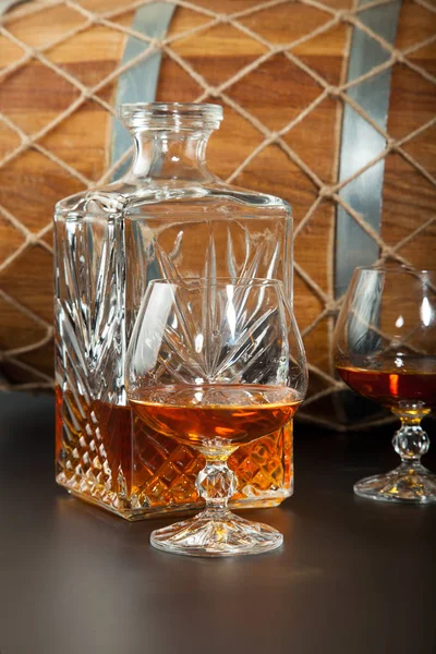 Glas brandy en een karaf op achtergrond eiken vaten — Stockfoto