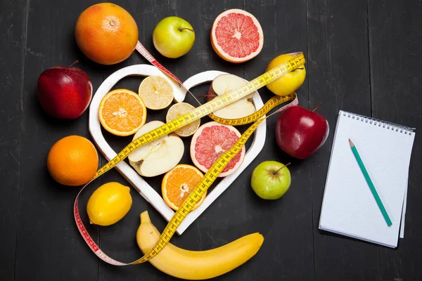Diet, fruits and centimeter on a black background