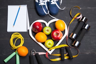 Kalp, meyve ve halter. Fitness, sağlıklı bir yaşam tarzı siyah ahşap zemin