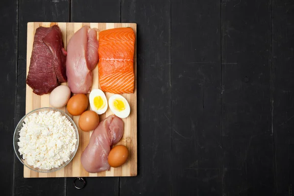Proteínas, pescado, queso, huevos, carne y pollo sobre fondo negro — Foto de Stock