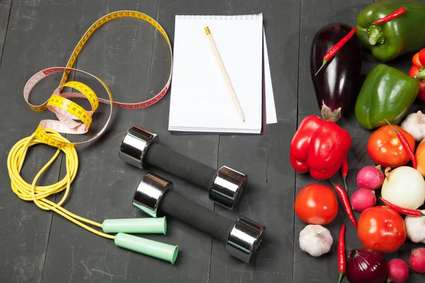 Sport e dieta. Uno stile di vita sano. Verdure, quaderni dei manubri. Peperoni, pomodori, aglio, ravanello di cipolla su fondo nero — Foto Stock