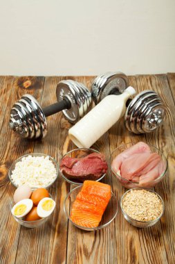 Protein, balık, peynir, yumurta, et, tavuk ve ahşap arka plan üzerinde halter