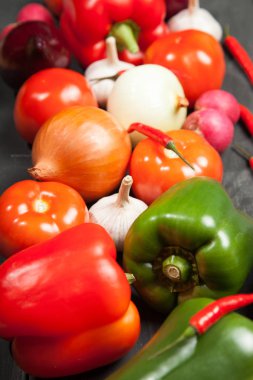 Sebze. Biber, domates, sarımsak, patlıcan, soğan ve turp siyah bir zemin üzerine
