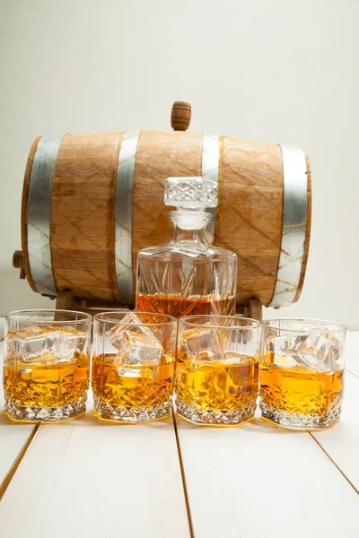 Vaso de whisky con hielo y una jarra en el fondo de barriles de madera —  Fotos de Stock