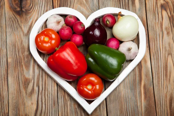 Sebze. Biber, domates, sarımsak, soğan ve turp rustik arka plan üzerinde kalbinde