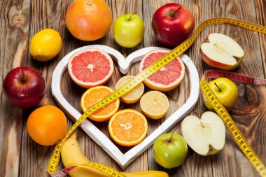 Meyve diyet, santimetre ve ahşap arka plan üzerinde bir kalp