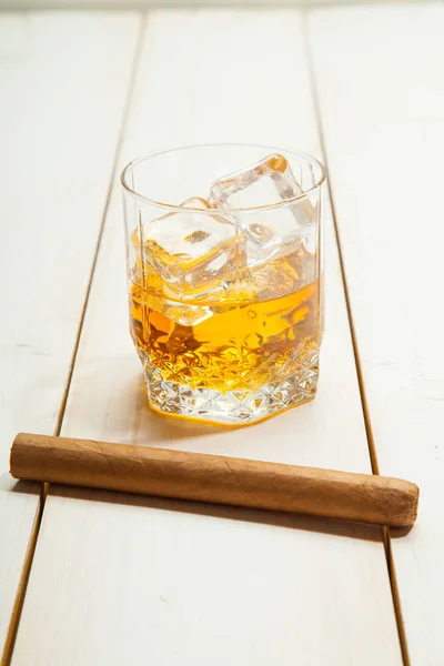 Стакан виски со льдом и сигарой на белом деревянном фоне — стоковое фото