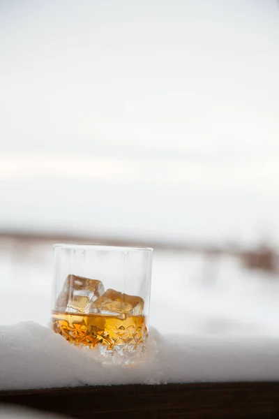 Szklankę whisky z lodem w śniegu na tło zima. — Zdjęcie stockowe