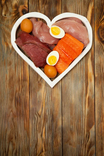 Eiwitten, vis, kaas, eieren, vlees, kip in een hart op houten achtergrond Rechtenvrije Stockfoto's